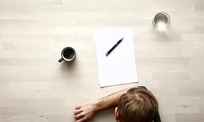 Me-time - omaa aikaa - Ylhäältä kuvattuna miehen pää, kirjoituspaperi ja kynä sekä kuppi kahvia