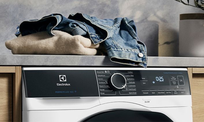 Electrolux-pyykinpesukone ja kasa vaatteita sen päällä odottamassa pesua