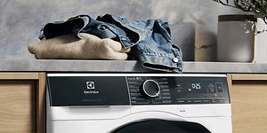 Electrolux-pyykinpesukone ja kasa vaatteita sen päällä odottamassa pesua