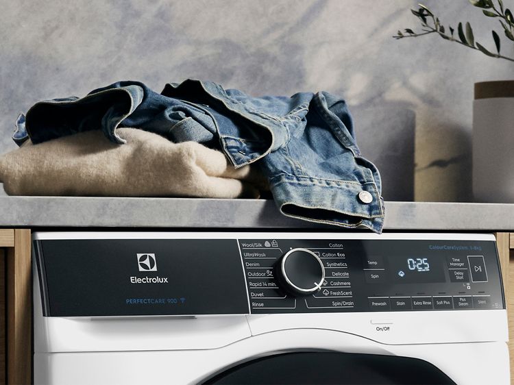 Electrolux-pyykinpesukone ja kasa vaatteita sen päällä odottamassa pesua