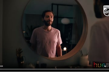 Philips Hue -videon kuvakaappaus, jossa mies seisoo katsomassa itseään peilin edessä