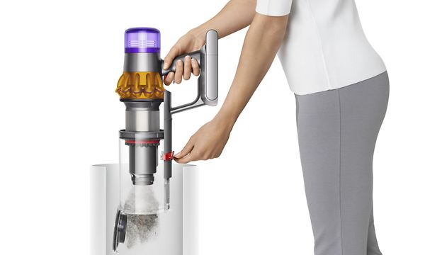 Henkilö tyhjentää Dyson-varsi-imurin pölysäiliötä
