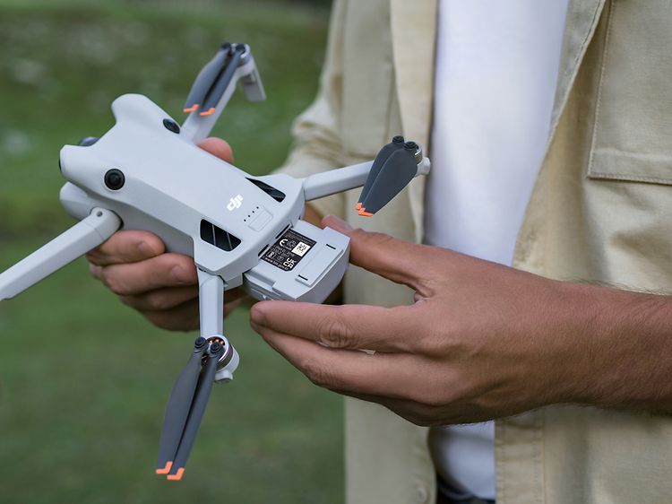 Tietokoneet - DJI - Henkilö pitää DJI Mini 4 Pro -dronea kädessään