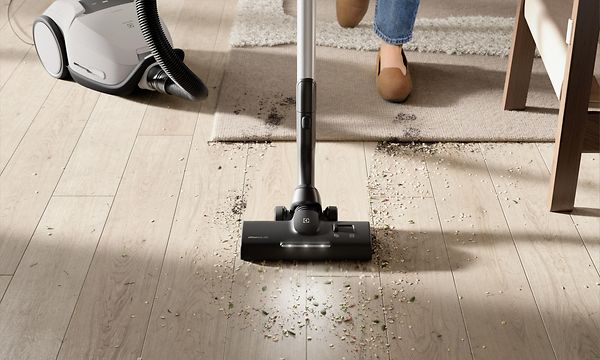 Nainen imuroi lattialle kertynyttä pölyä ja likaa Electrolux 800 -pölynimurilla