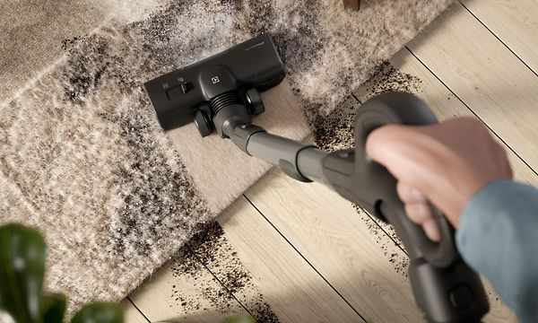 Henkilö imuroi mattoon kertynyttä likaa Electrolux 800 -pölynimurilla