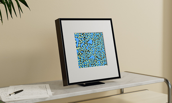 Samsung Music Frame jossa mustat kehykset avohyllyllä nuottien ja kynän vieressä