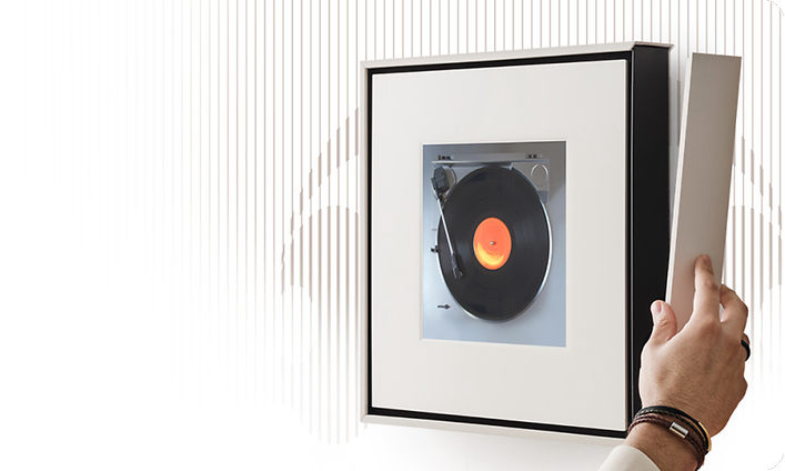 Henkilö kiinnittää valkoista kehystä Samsung Music Frame vasemmalle sivulle