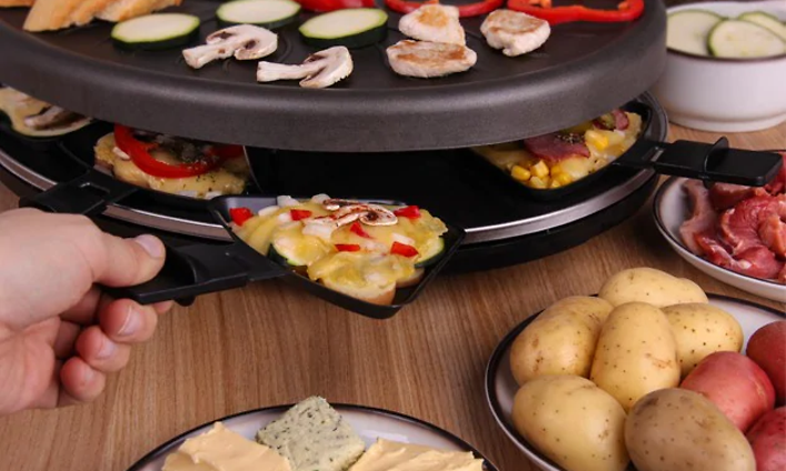 Henkilö tekee ruokaa raclette-pannulla