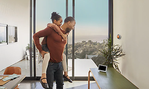 Mies kantaa tyttöä samalla katsoen Google Nest Hub -näyttöä