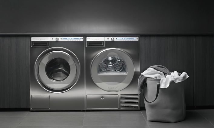 Teräksiset ammattitason pyykinpesukone ja kuivausrumpu vierekkän