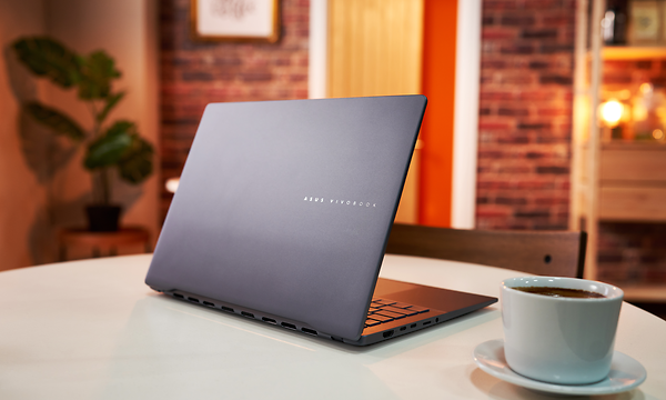 Asus Vivobook S 14 M5406 OLED kannettava tietokone pöydällä sekä kahvikuppi sen vieressä