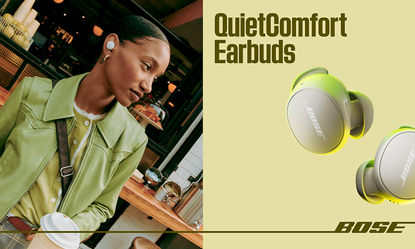 Nainen istuu kahvilassa QuietComfort-kuulokkeet korvissaan ja hänen vierellään näkyy toinen pari kuulokkeita lähikuvassa
