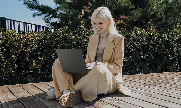 Nainen istuu terassilla ja työskentelee ASUS Zenbook S 16 -kannettavalla