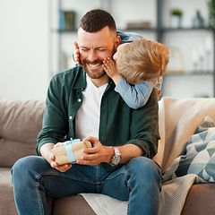 Mies istuu sohvalla ja saa lahjan pieneltä pojaltaan
