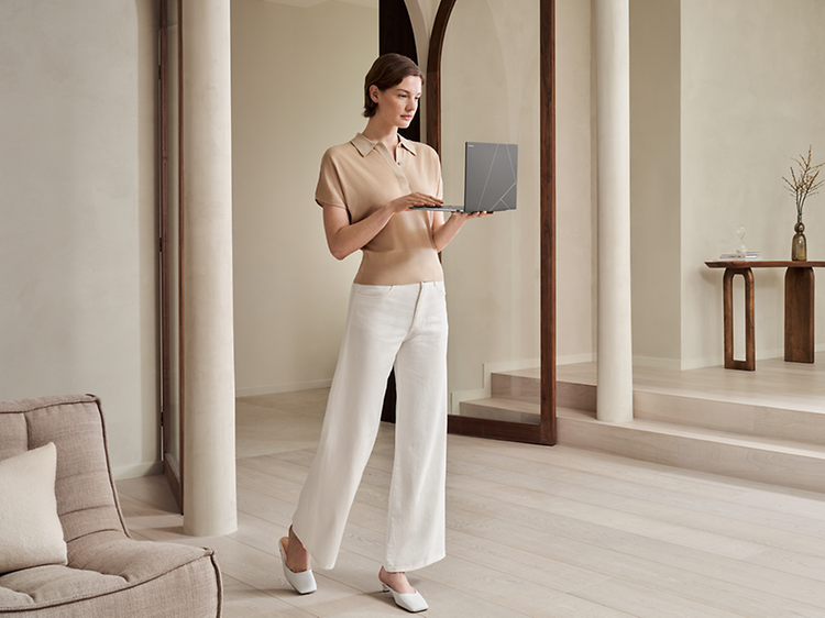 Nainen pitelee Asus Zenbook S 14 -kannettavaa