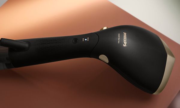 Philips - Kannettava vaatehöyrystin - Musta Philips-vaatehöyrystin ruskealla taustalla