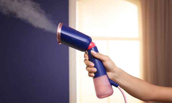 Philips - kannettava vaatehöyrystin - Sini-vaaleanpunainen Philips-vaatehöyrystin naisen kädessä