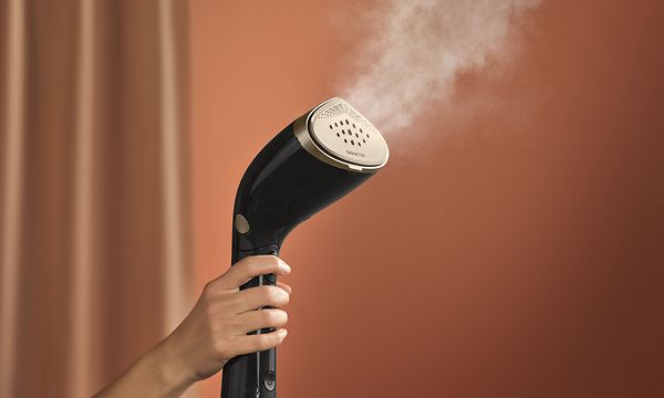 Philips - Kannettava vaatehöyrystin  - Musta Philips-vaatehöyrystin ruskealla taustalla