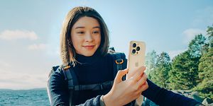 Reppu selässä oleva nainen repussa pitelee iPhone 16 Pro -älypuhelinta