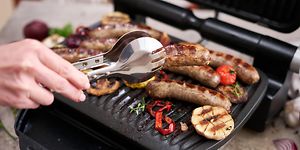 Henkilö grillaa lihaa ja kasviksia sähkögrillillä