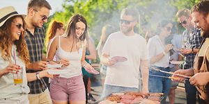 Joukko ystäviä on kerääntynyt grillaamaan ulkona aurinkoisessa säässä