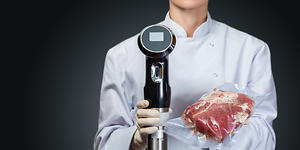 Sous Vide - Kokki pitää käsissään tyhjiöpakattua lihaa- ja sous vide -kiertovesipumppua