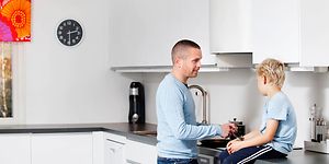Mies laittaa ruokaa pojan istuessa keittiön työtasolla