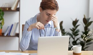 nainen työskentelee kannettavan tietokoneen kanssa väsynein silmin