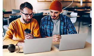 Kaksi miestä työskentelevät Lenovo ThinkBook -kannettaviensa parissa