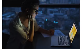 Nainen käyttää Lenovo ThinkBook -kannettavaa pimeässä huoneessa