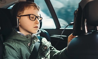 Poika istuu auton takapenkillä käyttäen etuistuimen takaosaan kiinnitettyä tablettia