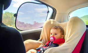 Aurinkosuoja auton ikkunassa ja vauva autonistuimessa