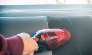 Handheld vacuum cleaner in red cleaning the car