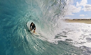 Mies surffaamassa suurenkokoisella aallolla