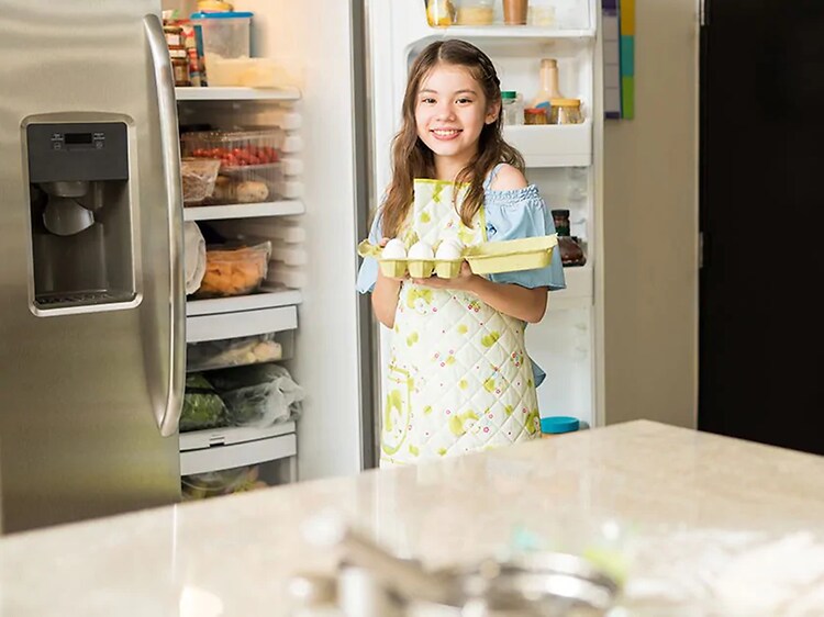 girl getting eggs from the two door refrigerator