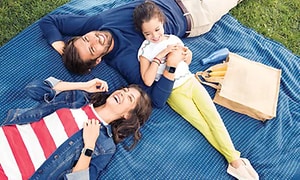 Perhe rentoutumassa ulkona piknikillä