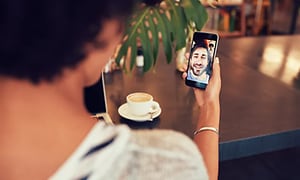 Nainen facetime-puhelussa miehen kanssa kahvikupin ääressä