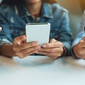 kolme teini-ikäistä käyttämässä älypuhelimiaan