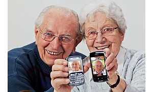 vanhemmalla pariskunnalla käsissään älypuhelimet, joissa kuvat toisistaan