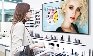 Nainen meikkikaupassa katsoo Samsung Business TV:tä