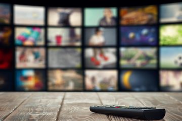 TV-kaukosäädin puupöydällä ja älytelevisio taustalla