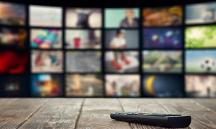 TV-kaukosäädin puupöydällä ja älytelevisio taustalla