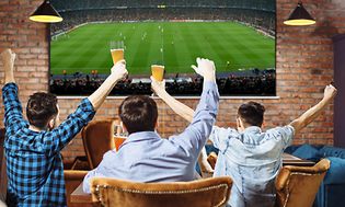3 guys cheering football on big screen TV in bar