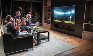 Guys in a living room watching football on big screen tv