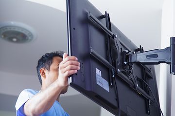 Mies asentamassa televisiota seinätelineeseen